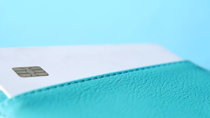 Three white plastic bank cards in teal leather wallet pocket on blue background