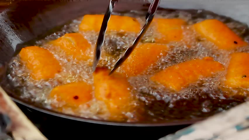 street food being fried in a pan and hot oil 