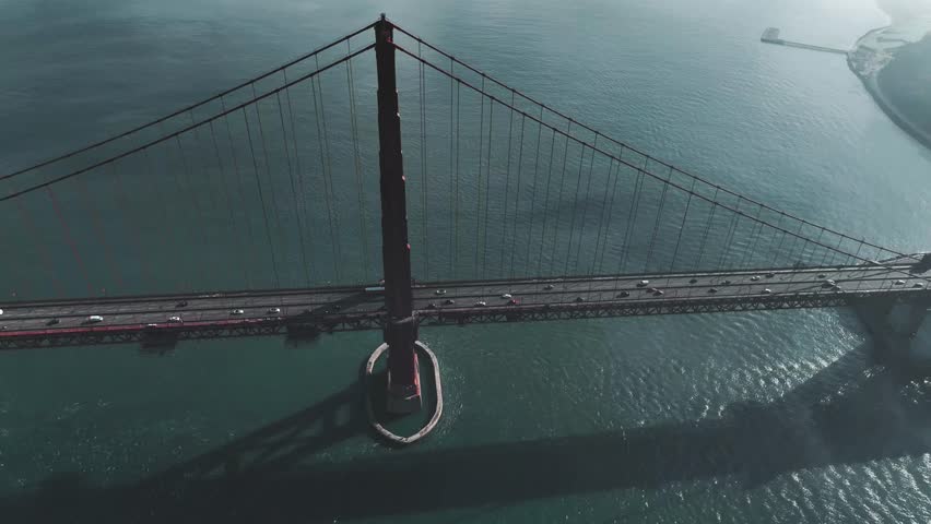Dramatic aerial orbit timelapse shot around the Golden Gate Bridge tower as thick fog rolls over the San Francisco Bay, California, USA.