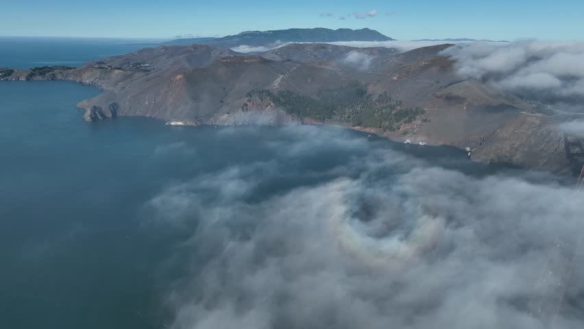 Dramatic pull out shot descending through thick white fog to unveil the iconic Golden Gate Bridge in San Francisco, California, majestic 4K aerial footage.
