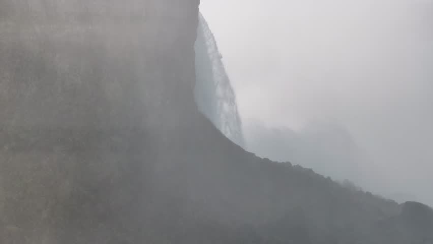 Majestic reveal shot rising through heavy mist to showcase the powerful Horseshoe Falls and observation deck in Niagara Falls, Canada, 4K aerial footage.