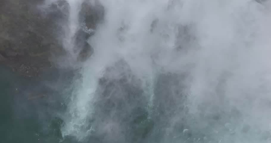 Aerial shot revealing the powerful crest and thick mist of Niagara Falls in Ontario, Canada, under an overcast sky.