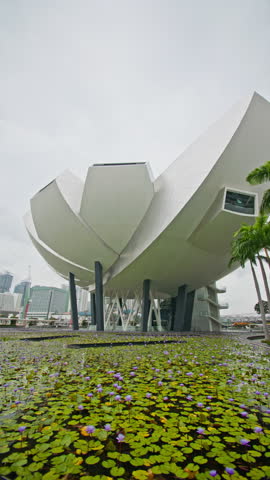 Lotus inspired ArtScience Museum in Singapore with futuristic architecture and cityscape skyline, flowers growing in water, iconic travel destination in Asia