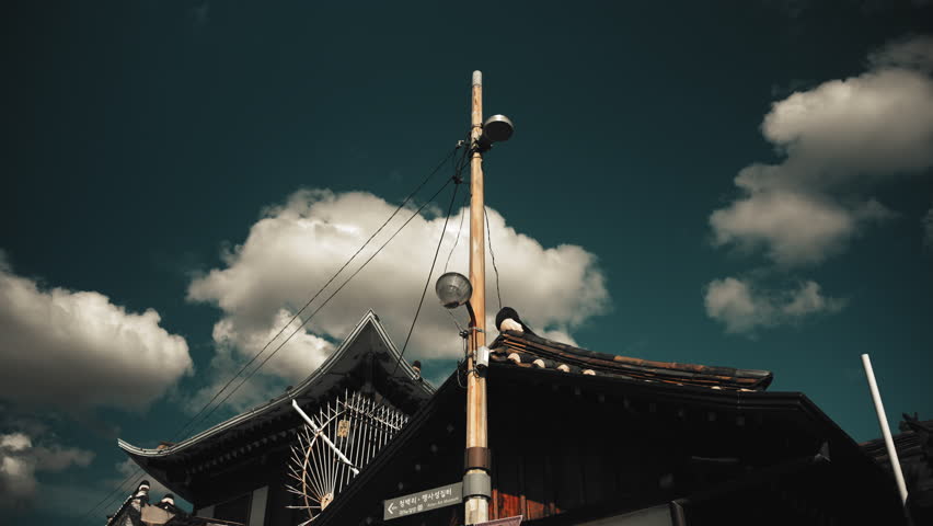 Traditional Korean Hanok Rooftop and Wooden Utility Pole Under Dramatic Blue Sky with Clouds in Seoul South Korea