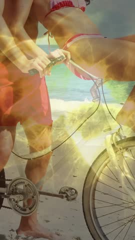 Vertical video: Beach woman on bike man holding bars cam pulling back flare sweeping sharing travel. Couple, romance, playful, laughter, bicycle, ocean, vertical video