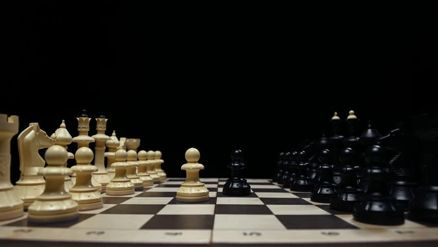 Chess pieces in close-up on a black background are facing each other. The player