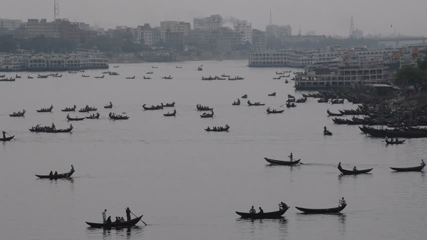 DHAKA, BANGLADESH – MAY 09: Small wooden boats are seen carrying passengers to cross the Buriganga river in Dhaka, Bangladesh on May 09, 2021.