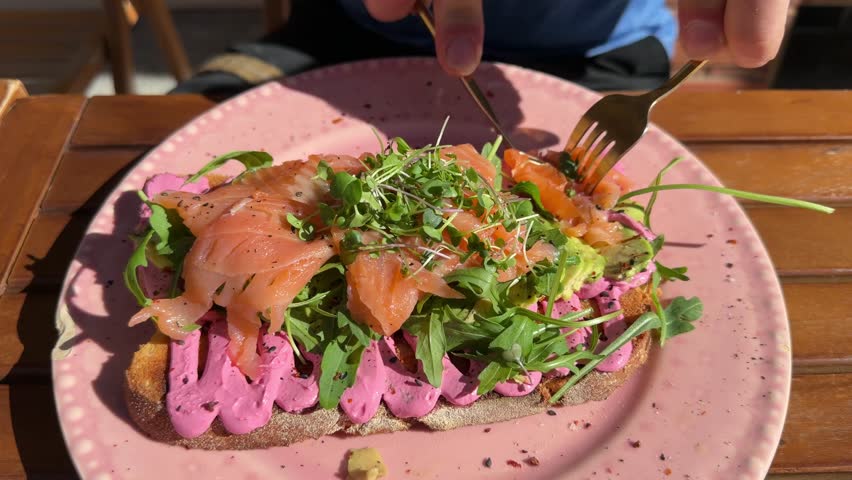 Top view of male hands cutting avocado toast with smoked salmon
