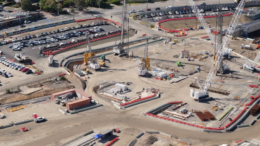 Aerial dolly over dusty construction site with large crawler cranes and piling machines. Construction on tunnel on outskirts of Melbourne CBD.