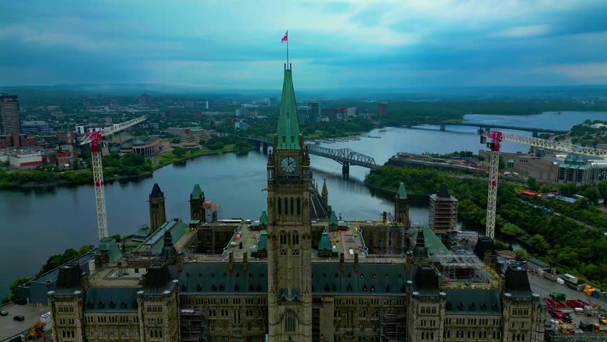 A drone captures footage of Parliament Hill as it approaches the clock tower overlooking the background of the Ottawa River, which forms the border between Ontario and Quebec on a cloudy afternoon 2-3