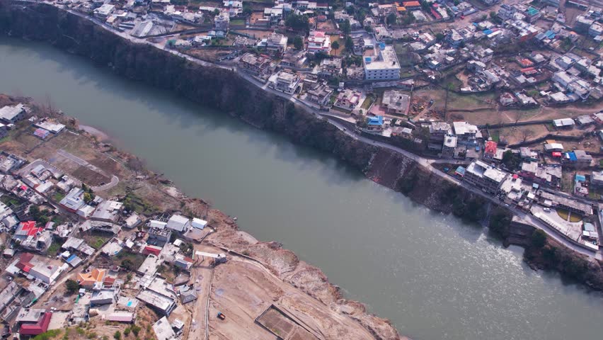Jhelum River cutting through Muzaffarabad with cliffs and riverside homes. Muzaffarabad