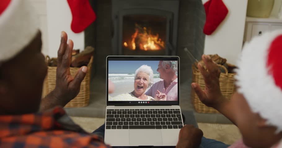 African american couple with santa hats using laptop for christmas video call with couple on screen. christmas, festivity and communication technology.