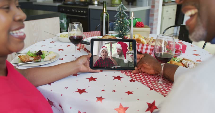 Smiling african american couple using tablet for christmas video call with happy family on screen. christmas, festivity and communication technology.