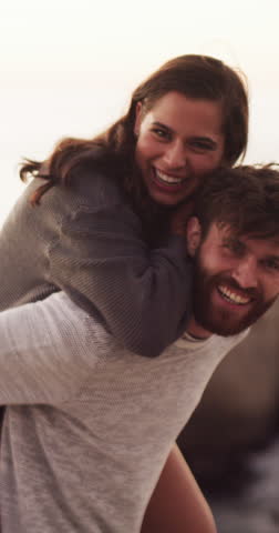 Face, piggyback and happy couple at beach for love, bonding and travel in nature together. Holiday, smile and excited people at sea with romance, date and carrying for vacation in California