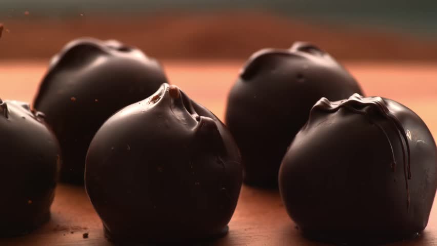 Sprinkle cocoa powder on gourmet chocolate truffles, an elegant dessert concept.