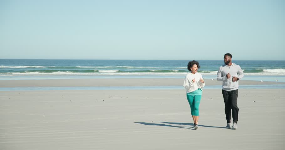 After jogging on sandy beach Diverse couple in sportswear warming and stretching with smartwatches. Athletics, wellness, leisure, outdoor, harmony, fitness, motivation