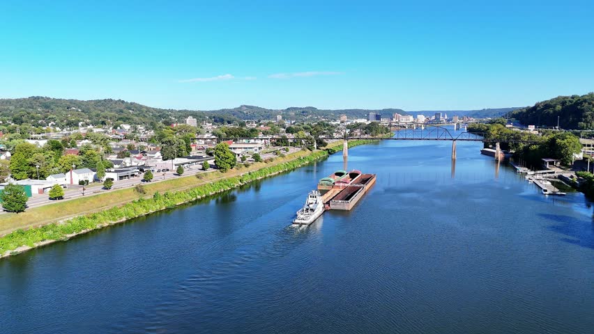 The South Charleston City river scene featuring multiple bridges With Railroad Bridge named the Travis L. Castle Railroad Trestle spanning the wide blue Kanawha River, with green hills in distance.