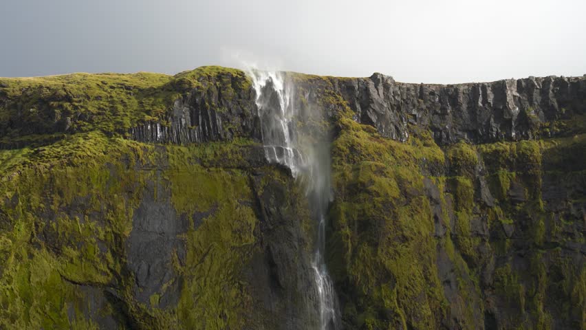 High Waterfall Tucked Away In A Mossy Canyon In South Iceland. Slow Motion Shot