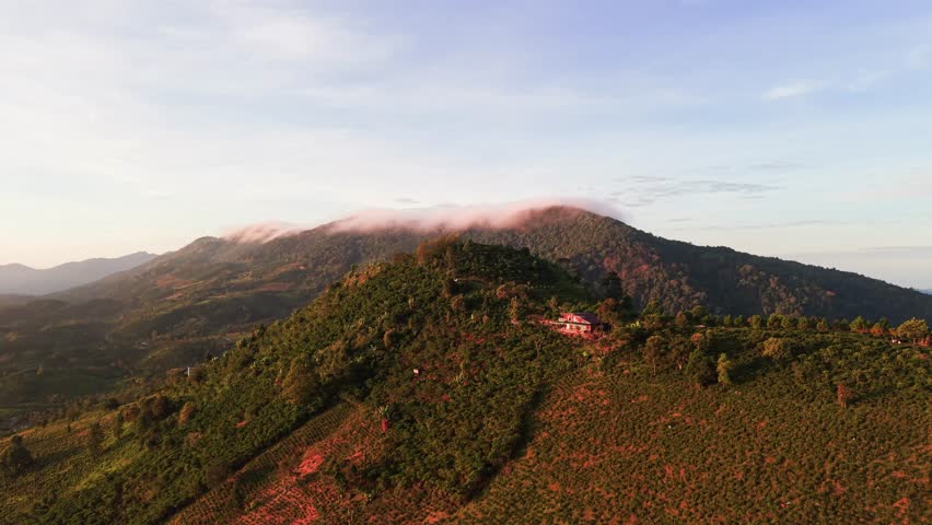 Exploring a mountain landscape in the early morning light with green hills and a farmhouse in the distance.