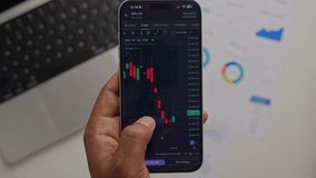 Stock Exchange Broker Analyzing Real-Time Stocks and Exchange Market Charts on Smartphone Using Online Trading App. Investment Agent Working in Office. Close Up. - Powered by Shutterstock - Get 15% off with code: PIKWIZARD15
