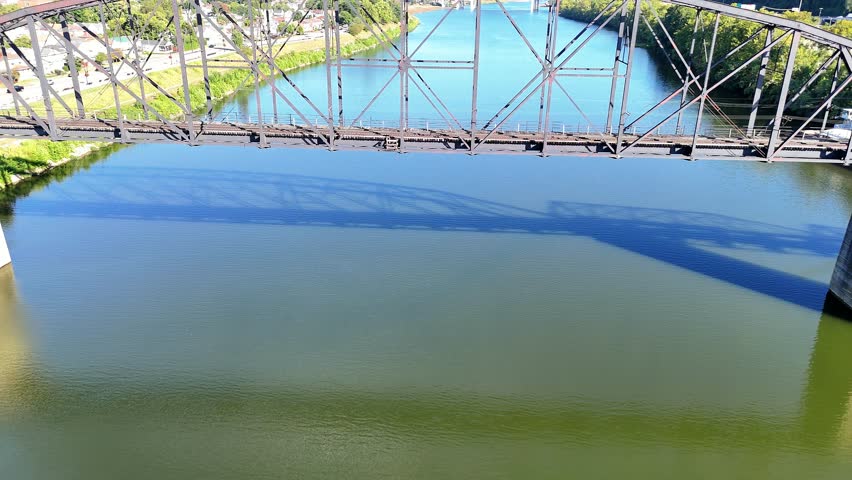 The South Charleston City river scene featuring multiple bridges With Railroad Bridge named the Travis L. Castle Railroad Trestle spanning the wide blue Kanawha River, with green hills in distance.