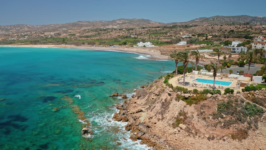 Cyprus beautiful coastline featuring luxury resort with a swimming pool, nestled on a cliff overlooking the clear turquoise Mediterranean Sea and a sandy beach. Nature landscape aerial view drone shot