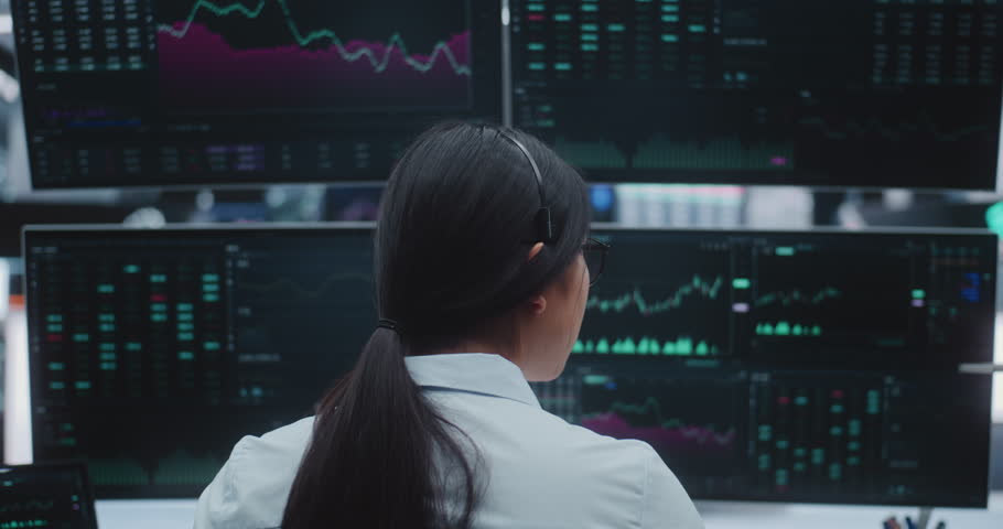Asian Female Broker Monitors Real Time Indices in Massive Digital Trading Room. Concept of Corporate Strategy, Institutional Investing and Innovative Corporate Infrastructure in Heart of City.