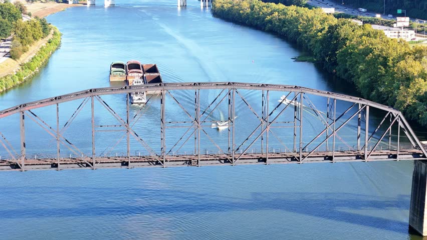 The South Charleston City river scene featuring multiple bridges With Railroad Bridge named the Travis L. Castle Railroad Trestle spanning the wide blue Kanawha River, with green hills in distance.