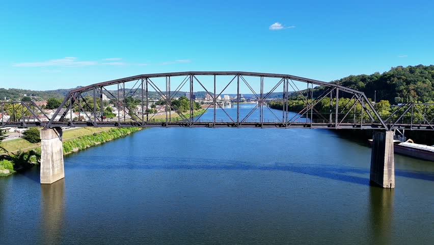 The South Charleston City river scene featuring multiple bridges With Railroad Bridge named the Travis L. Castle Railroad Trestle spanning the wide blue Kanawha River, with green hills in distance.
