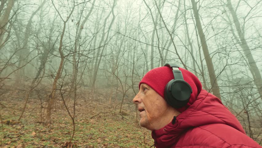 Quiet hike in a foggy green forest. Moody atmosphere and cinematic nature shot of a man on a trail.
