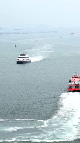 High-speed ferries navigating Hong Kong harbor waters with wake trails under overcast sky