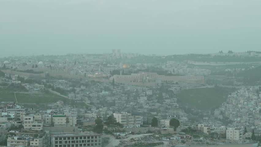 Cinematic view of the historic Old City walls, the Dome of the Rock, and the Temple Mount in Jerusalem. A look at the holy site sacred to Judaism and Islam, captured during a hazy day with low visibil