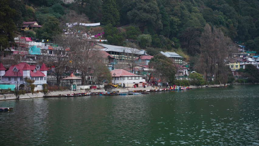 Peaceful view of Nainital Lake and buildings against mountain backdrop with calm waters and houses