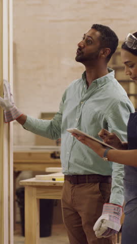 People, carpenter and board at workshop with planning, tablet and discussion with furniture design. Man, woman and artisan team with woodwork, tech and application for project management at factory