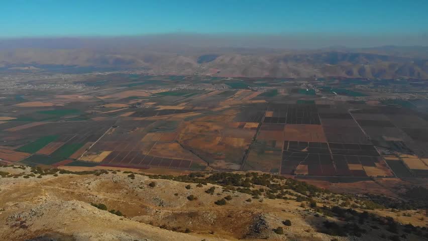 Drone aerial of Bekaa Valley showing vast agricultural fields and mountain landscape. Scenic rural farmland panorama with patchwork crops and natural terrain.