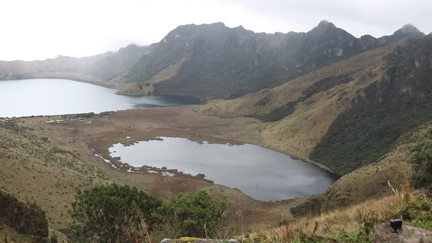 Handheld panoramic view sweeping left across Mojanda volcanic lakes and dramatic Andean peaks in Ecuador, ideal for travel, nature, and documentary productions.