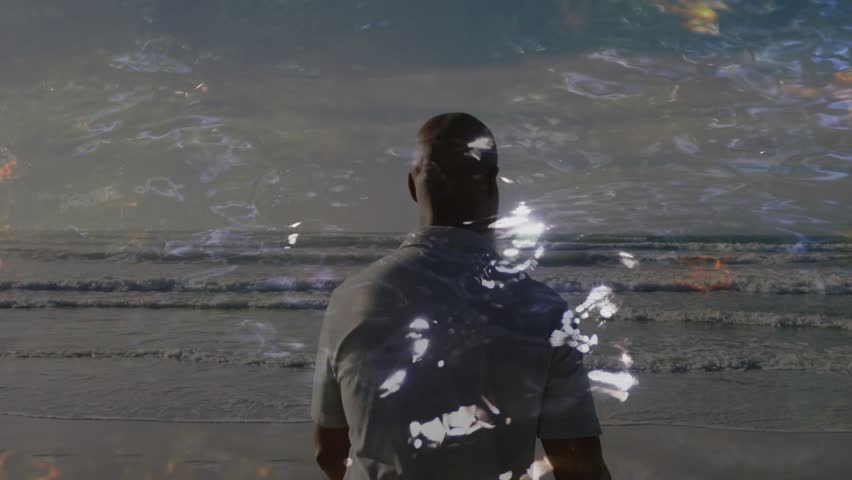 Man walking shoreline as water sparkles and flame overlays rising, drawing him toward sphere, tech. Beach, horizon, orb, glow, sea, individual, contemplative