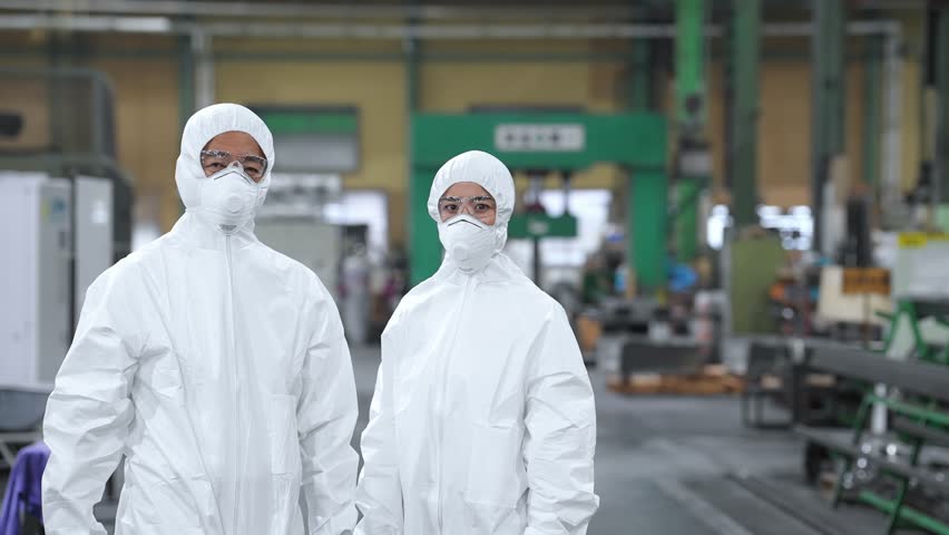 Male and female workers wearing protective clothing standing in a factory