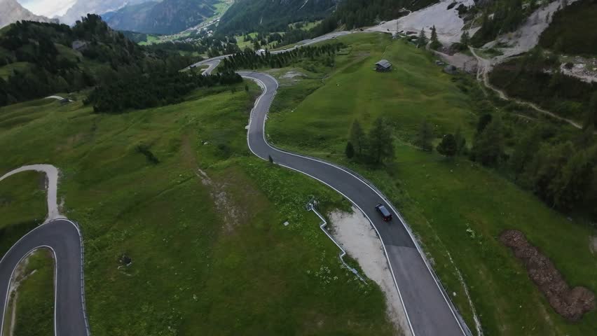 Aerial View Winding Road Dolomites, Solitary Car Travels Along Smooth Asphalt Through Green Alpine Meadows By A Lone Hut, Tranquil Summer Light, Sweeping Panorama Captured By Drone, Serene Travel Mood