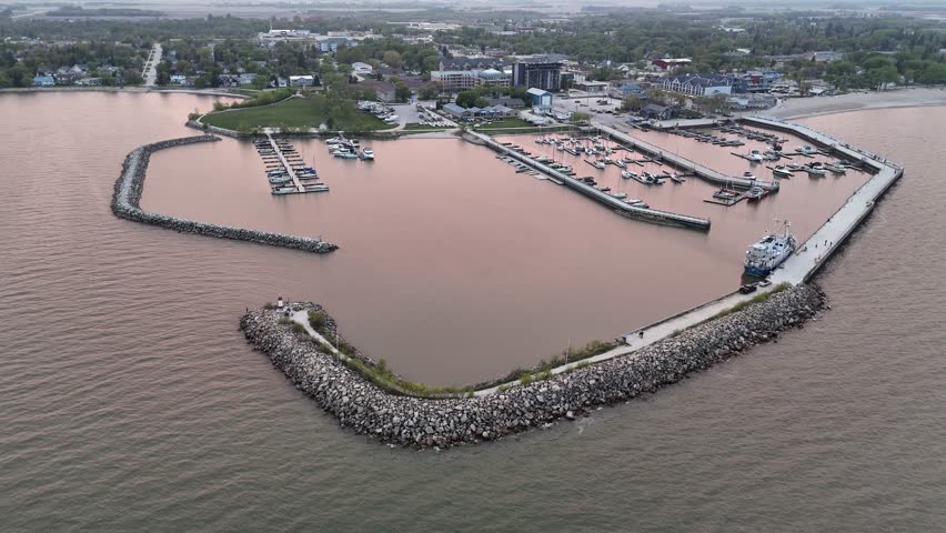 Drone aerial over Lake Winnipeg at Gimli Harbour, Manitoba, facing the town while slowly rotating right. Scenic waterfront marina and shoreline in the New Iceland community.