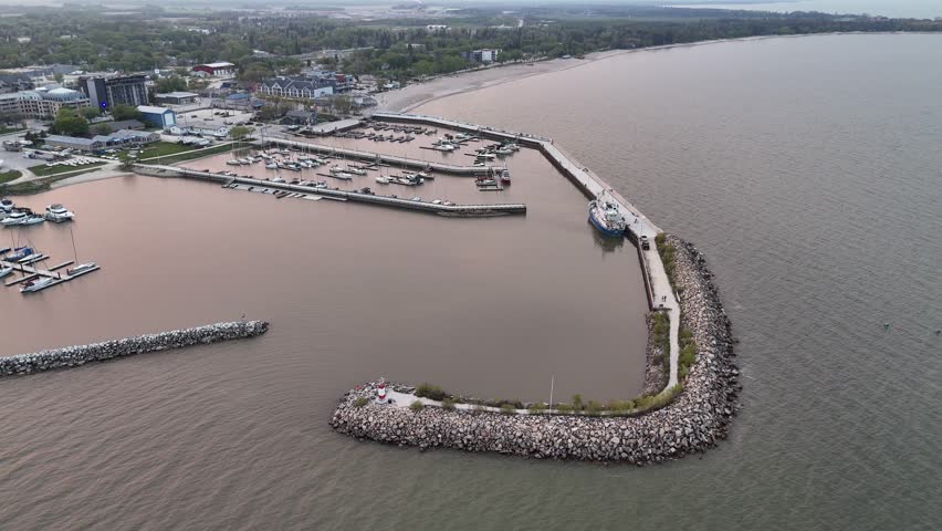 Drone aerial over Lake Winnipeg at Gimli Harbour, Manitoba, facing the town while slowly rotating right. Scenic waterfront marina and shoreline in the New Iceland community.