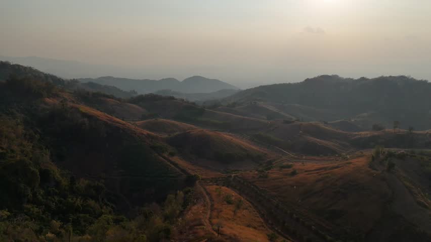 Aerial video of a vast mountain range in the evening as the sun is setting.