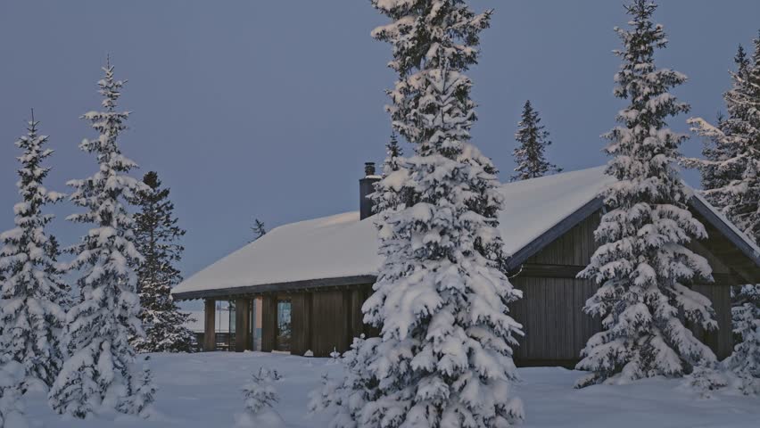 Cozy cabin in Sjusjøen, Norway, at blue hour, featuring a secluded wooden lodge surrounded by snow-laden pine trees under a tranquil twilight sky.