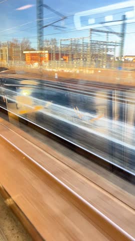 A train is moving past a building with a lot of wires. The train is blurry, and the background is hazy
