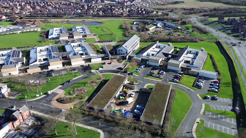 Hopewood mental hospital aerial orbit over Ryhope, Sunderland. Modern NHS psychiatric facility campus, car parks, roads and green spaces on a clear day, UK healthcare infrastructure.