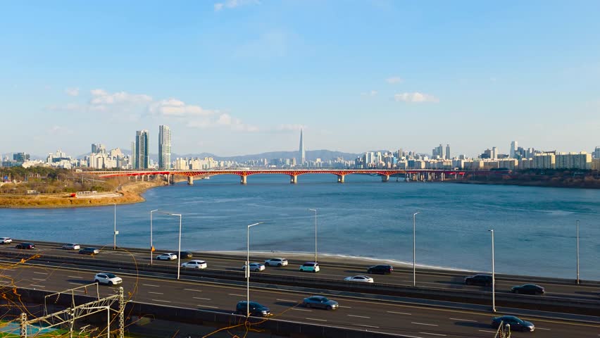 Real-time zoom over Gangbyeonbuk-ro expressway traffic toward Seongsu Bridge and Lotte World Tower across Han River in Seoul