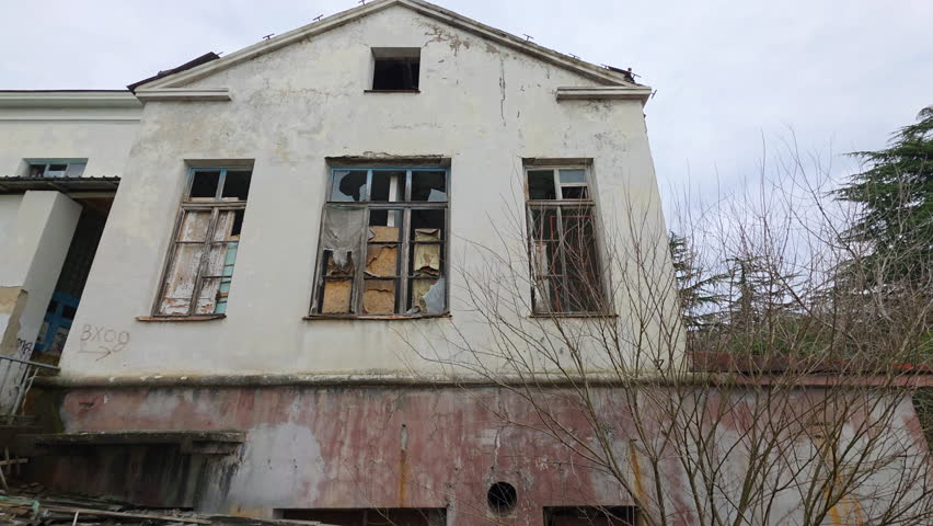 Ruined facade of an abandoned building with broken windows and decaying walls, a spooky and desolate structure showcasing urban decay and neglect in a haunted atmosphere