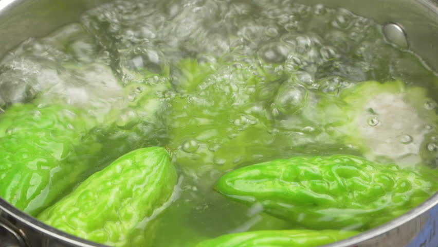Close up of hands using chopsticks to stir traditional Vietnamese stuffed bitter melon soup with minced pork vigorously boiling in a pot for Lunar New Year