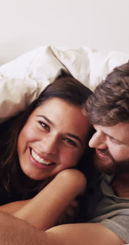 Cover, face and laughing with couple in bed together for moment, morning bonding or wake up. Blanket, funny and love with happy people in bedroom of home for relationship, security or wellness