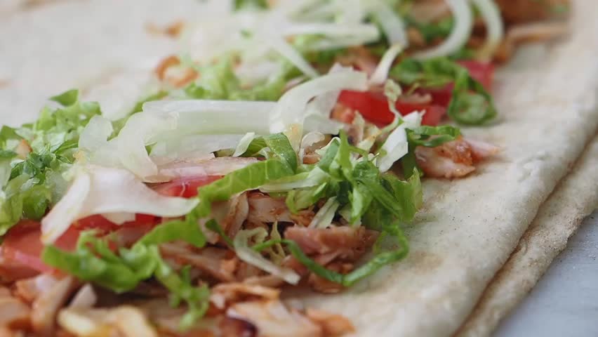 Shawarma wraps being prepared with fresh vegetables and savory sauce